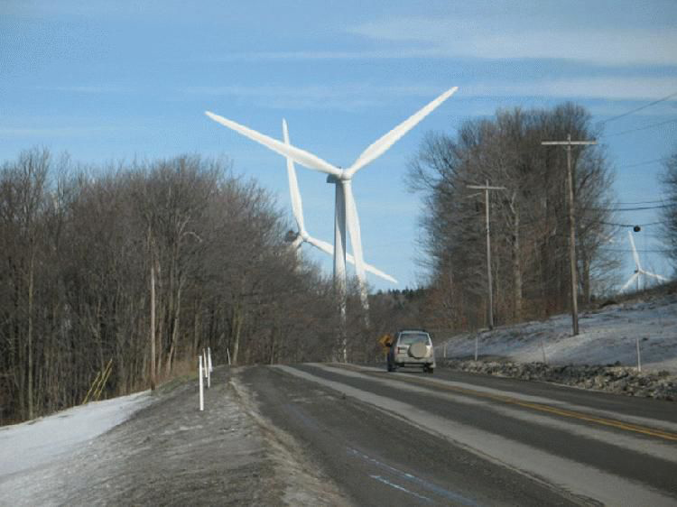 Car on a dirty snowy road with giant wind turbines in the distance